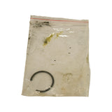 Close-up of small clear ziplock bag containing a single black circlip/snap ring. Bag shows dirt and age marks but is sealed.